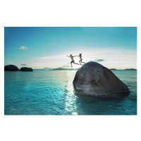 Umělecká fotografie Two kids holding hands jumping off rock into sea, Gary John Norman, (40 x 26